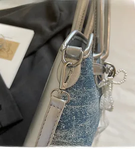 Détail du sac en denim bleu avec strass brillants, boucles argentées et perles blanches