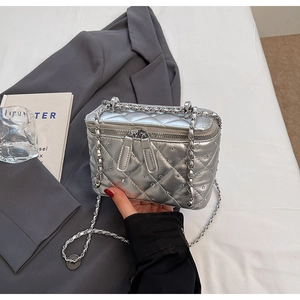Detail of silver quilted bucket bag with metallic finish on dark grey blazer