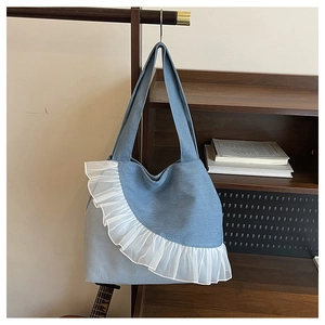 Detail of light blue denim tote bag with white organza ruffled edges on wooden hanger