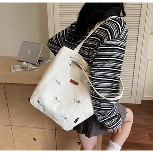 Detailed embroidery of a dachshund on a white canvas tote bag with brown leather accents