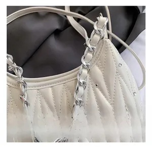 Detail einer weißen Stepptasche mit Kristallbesatz und silberner Kettenriemenbefestigung