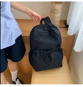 Detail view of water-resistant nylon backpack showing front drawstring pocket and handle