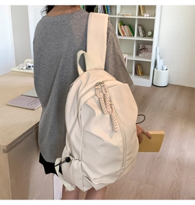 Side view of a creamy white large capacity nylon backpack with woven zipper pulls and side pockets