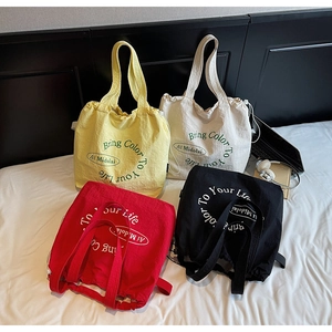 Multiple casual canvas tote bags in various colors displayed on a white bed