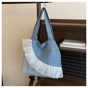 Detail view of denim tote bag featuring white organza ruffles and long shoulder straps