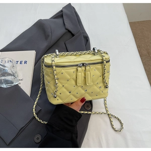 Detailed macro view of yellow quilted crossbody bag with sparkling rhinestone embellishments