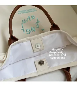 Detailed top view of the canvas tote bag showing magnetic buckle and leather handles