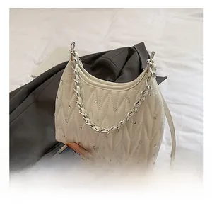 Detail der cremefarbenen Stepptasche mit Strasssteinen und silberner Kette