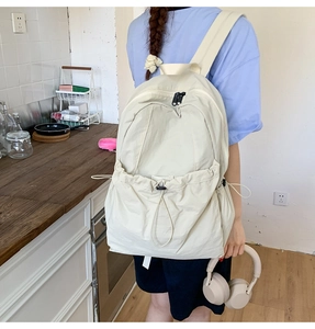 Detail of off-white nylon backpack with decorative drawstring and large front pocket