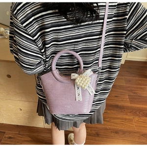 Detail view of lavender faux crocodile handbag with white lace bow and pearl charm