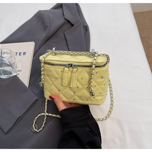 Detail of yellow quilted chain bag with rhinestone accents and silver chain strap