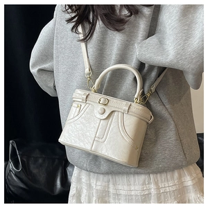 Detail of off-white box bag with lychee texture leather and unique button decoration