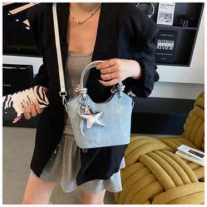 Detail of light blue denim bucket bag with silver star charm and metallic handle
