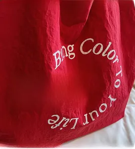 Detail of red canvas tote bag with white text print and natural textured fabric