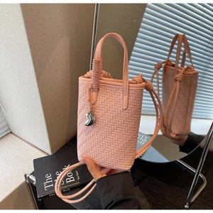 Détail du sac seau tissé rose avec pendentif en métal argenté en forme de haricot
