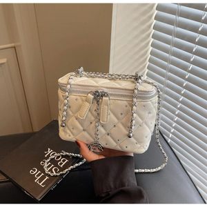 Detail of cream quilted bag with rhinestones, silver chain, and rose pendant zipper