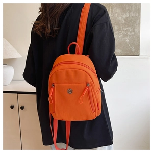 Détail du mini sac à dos en nylon orange vif avec une poche frontale zippée pratique