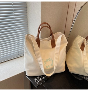 Détail du sac cabas en toile blanche avec anses en cuir marron et imprimé vert