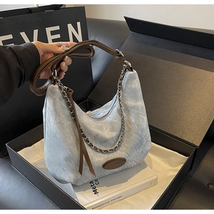 Detailansicht einer Denim Hobo Bag mit Lederriemen und Kette in einer Premium-Geschenkbox