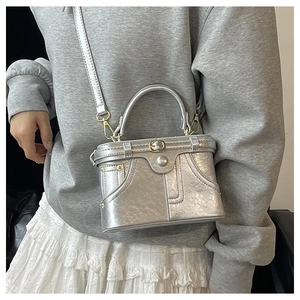 Silver metallic crossbody bag featuring creative denim waistband design and belt buckle detail