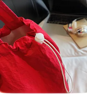 Detail of red drawstring closure with white plastic toggle on waterproof nylon bag