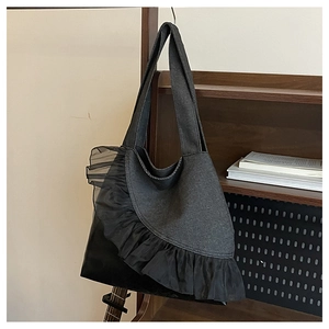 Detail view of denim tote bag with black lace ruffle trim hanging on a wooden shelf