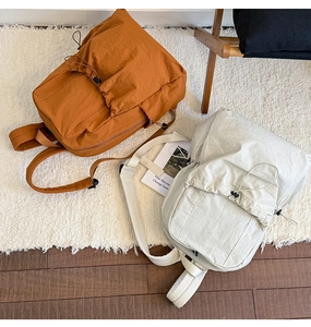 Top view of two casual nylon backpacks in orange and cream on a cozy rug and wooden floor