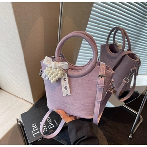 Detail view of lilac crocodile pattern PU handbag with pearl lace bow charm