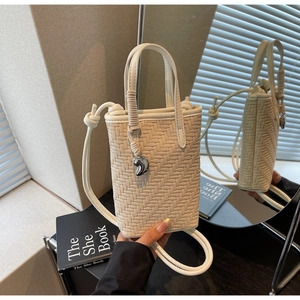 Détail d'un sac seau tressé avec poignée enroulée de corde et pendentif en cœur