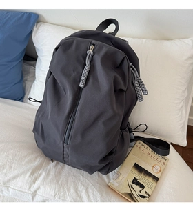 Detail of gray waterproof nylon backpack featuring vertical zipper and woven puller