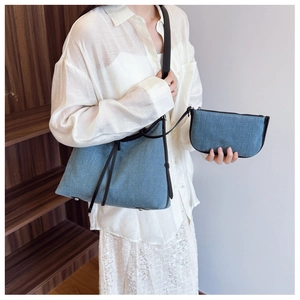 Detail of blue denim tote bag and pouch set with black leather straps and fringe