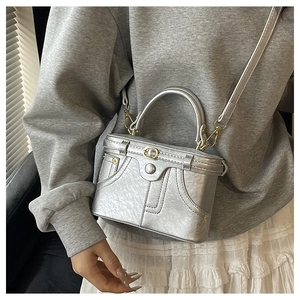 Detail of silver metallic handbag with unique clothing-inspired buckle and leather texture