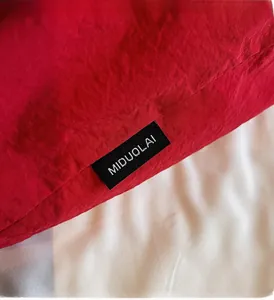 Detailed macro shot of red canvas fabric texture with black woven MIDUOLAI brand label