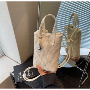 Détail du mini sac seau tressé blanc avec breloque argentée et options de double bandoulière