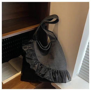 Detail of black denim tote bag with sheer mesh ruffle trim and integrated wide shoulder strap