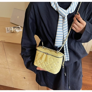 Detail of yellow quilted crossbody box bag with rhinestone accents and silver chain strap