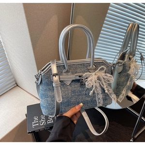 Gros plan du sac en denim bleu clair avec garniture argentée et charm noeud en dentelle et perles