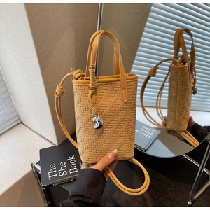 Détail du sac seau jaune tressé avec pendentif demi-lune argenté et bandoulière