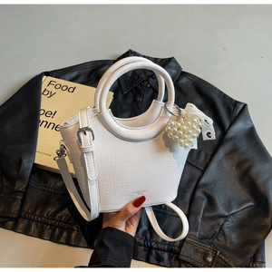 Detail of white crocodile texture bucket bag with pearl heart charm and metal ring handle