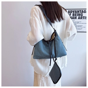 Detail of blue denim hobo tote bag with leather straps and matching small pouch