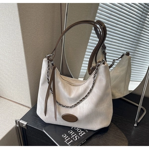 Detail der hobo-tasche aus creme-leinen mit braunem leder und metallkette auf spiegel