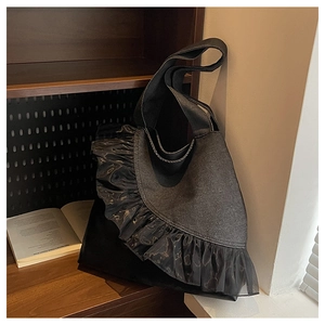 Detail of black tote bag with large decorative tulle ruffles and wide shoulder strap