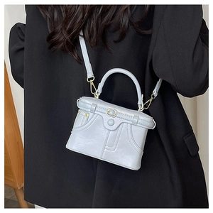 Close-up of light blue mini handbag with unique buckle detail and detachable strap on model