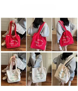 Detail view of large canvas tote bags in red and off-white with printed slogan design