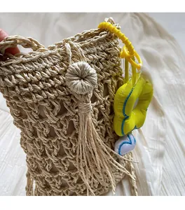 Dettaglio della borsa in paglia beige fatta a mano con fibbia rotonda e ciondolo a fiore
