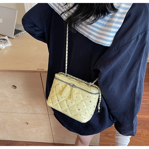 Detail of yellow quilted vanity bag with rhinestone studs and metal chain strap