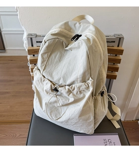 Detail of off-white nylon backpack showing wrinkled fabric texture and drawstring pocket