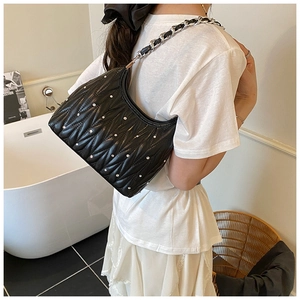 Detail der schwarzen Stepptasche mit glitzernden Kristallen und silberner Kette