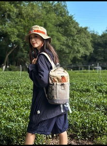Detail of khaki outdoor backpack with orange zipper accents and mesh side pocket