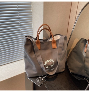 Détail du sac cabas en toile grise avec anses en cuir marron et large bandoulière